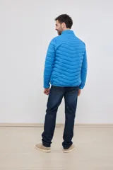 Campera capitoneada liviana de color azul con cuello alto e interior a contratono. Presenta un diseño con costuras horizontales, cierre frontal completo y dos bolsillos laterales con cremallera.