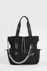 Cartera shopper negra de nailon, con doble asa de hombro, bolsillos laterales, bolsillo frontal de red y correa decorativa de cordón trenzado en blanco y negro con mosquetones.