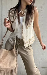 Chaleco color natural, sin mangas, con diseño abierto al frente y detalles de bordados étnicos en tonos marrones y dorados.