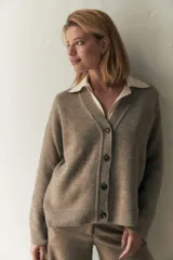 Cárdigan color crema de tejido de punto industrial con escote en V, combinación de puntos y botones decorativos en las mangas.