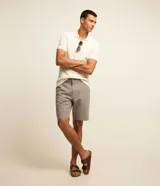 Bermuda masculina de corte recto confeccionada en sarga de algodón. Presenta cierre frontal con botón y cremallera, bolsillos laterales y traseros, y diseño liso sin estampados.