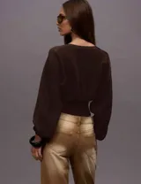 Sweater de tejido de punto color chocolate, con diseño de mangas amplias y cintura ajustada con elástico ancho. Presenta un corte relajado en la parte superior y un ajuste ceñido en la cintura que estiliza la silueta.