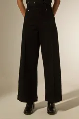 Pantalon de jean negro de tiro alto, con corte ancho y costuras verticales decorativas en el frente.