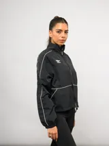 Campera deportiva Umbro de nylon color negro, con cuello alto, cierre frontal y detalles de líneas blancas en contraste. Presenta bolsillos laterales y puños elásticos.
