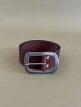 Cinturón de cuero color marrón chocolate con hebilla metálica y logo de la marca grabado tanto en la hebilla como en la tira de cuero.