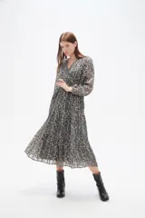 Vestido midi de corte evasé con estampado animal print en tonos oscuros. Presenta escote en V cruzado, mangas largas con puños y falda con volados escalonados.