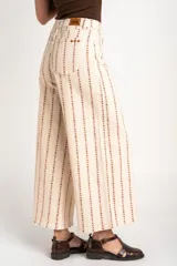 Pantalón jean wide leg de tiro alto, color beige con estampado vertical de líneas y flores marrones, de corte holgado y diseño de cinco bolsillos.
