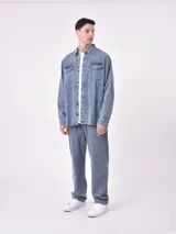Sobrecamisa de jean celeste con dos bolsillos frontales con solapa y cierre con botones.
