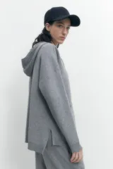 Sweater gris melange de tejido de punto, con capucha y cordones cruzados en el escote.
