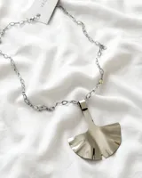 Collar con cadena de eslabones plateada y dije de alpaca con forma de hoja de ginkgo biloba.