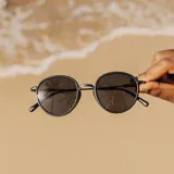 Lentes de sol Sunski Baia con montura redonda negra y detalles metálicos plateados. Lentes polarizados verdes que bloquean el 100% de los rayos UVA/UVB/UV400.