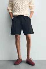 Bermuda de algodón rizo (tipo toalla) color azul marino, de corte regular fit. Presenta cintura elástica con cordón interno ajustable, bolsillos frontales y un bolsillo trasero de plastrón. Los bordes tienen un ribete blanco a contraste.