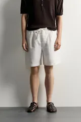 Bermuda de lino negro de corte relaxed fit, con cintura elástica ajustable mediante cordón y bolsillos frontales.