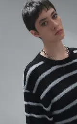 Sweater de cuello redondo con diseño de rayas horizontales en negro y gris. Presenta una textura suave y peluda, con terminaciones en punto rib en el cuello.