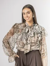 Camisa de seda italiana con diseño reversible, que permite usar el lazo de ajuste tanto en la parte frontal como en la posterior. Presenta un corte holgado con volados en el frente y mangas largas con puños elásticos. Su estampado sutil combina tonos tierra con motivos de animal print.