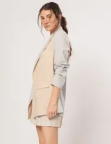 Blazer oversized de corte recto en lino, color beige y gris. Largo a la cadera, con hombreras finitas forradas, costuras internas con sesgo combinado y bolsillos delanteros.