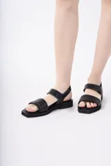 Sandalias negras de cuero con punta cuadrada, tiras capitoneadas y pespuntes blancos a contratono.