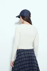 Top de tejido acanalado color negro, con escote en V y cierre frontal mediante cordones ajustables con ojales metálicos. Presenta mangas largas y un corte entallado al cuerpo.