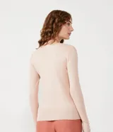 Suéter de punto color rosado, con cuello barco, mangas largas y puños con botones decorativos. El dobladillo también es acanalado.