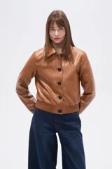 Chaqueta estilo bomber corta de eco-cuero color caramelo, con cuello camisa, cierre frontal de botones oscuros y puños y cintura de tejido acanalado.