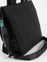 Cartera tipo shopper de color beige con diseño matelaseado de líneas onduladas y costuras en contraste azul. Cuenta con doble asa de hombro y un colgante decorativo de cordones multicolor en uno de sus laterales.