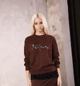 Sweater de punto color marrón con cuello redondo y puños acanalados. Presenta un bordado en el pecho con la frase 'the farra' en color celeste y un detalle de flecos negros en el ruedo.