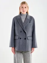 Chaqueta de paño gris de corte amplio, con solapas clásicas, cierre frontal cruzado de botones y bolsillos laterales con solapa.
