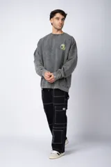 Buzo de cuello redondo y corte oversize, confeccionado en tela friza con efecto de teñido artesanal desgastado. Presenta un estampado pequeño en color verde lima en el pecho y una etiqueta pequeña en el puño.