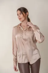 Blusa color beige de seda, manga larga ranglan y bolsillo delantero.