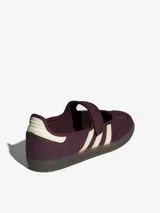 Zapatillas Adidas modelo Samba Jane, color bordó con detalles en blanco. Presentan un diseño tipo Mary Jane con cierre de velcro en el empeine, manteniendo la estética clásica de las Samba con las tres tiras laterales y suela de goma.