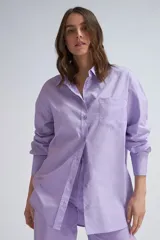 Camisa oversize color lavanda de poplin con cuello clásico, cierre frontal con botones, manga larga con puños abotonados y bolsillo de parche en el pecho.