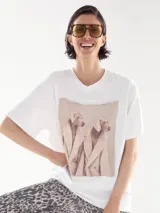 Remera blanca de corte recto con estampa de dos perros caniches vestidos con abrigos.