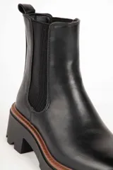 Bota marrón de cuero sintético, estilo Chelsea, con punta redonda, pieza elastizada en los laterales y suela tipo tractor de 6cm de alto.