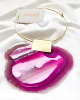 Collar rígido dorado con dije rectangular dorado.