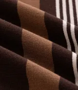 Suéter de punto Marfinno con cuello redondo y mangas largas. Presenta un diseño de rayas horizontales en tonos marrones y beige sobre una base de color marrón oscuro.
