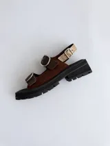 Sandalias de cuero charolado bordó con punta redonda, suela flatform chunky negra con ranuras, y dos tiras frontales con grandes hebillas metálicas plateadas y una tira trasera ajustable.