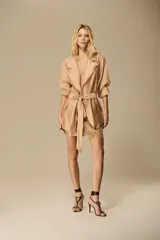 Blazer de organza color blanco marfil, con solapas clásicas, bolsillos frontales aplicados, mangas largas y faja del mismo material para ajustar en la cintura.