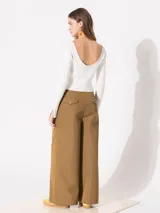 Pantalón negro de gabardina con pata ancha y doble cintura: una de tela base con gancho pantalonero y otra interna de poliéster con elástico y botón. Tiene bolsillos laterales.