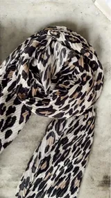 Pañuelo de textura plisada con estampado animal print en tonos beige, negro y marrón.