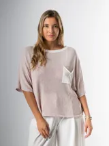 Remera tejida color crema con cuello redondo y bolsillo frontal verde.