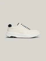 Zapatillas Tommy Hilfiger de cuero color blanco con detalles en azul marino. Presentan cordones azul marino, suela gruesa blanca y logo de la marca en el lateral.