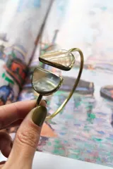 Pulsera dorada tipo brazalete con apliques de nácar en los extremos.