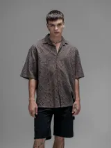 Camisa clásica de manga corta, color chocolate con efecto desgaste, confeccionada en algodón bordado (broderie) con diseño floral calado. Presenta cuello abierto y calce oversize.