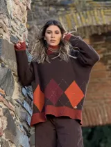 Sweater de punto con diseño de rombos en tonos marrones, naranjas y bordó. Presenta cuello alto, mangas largas con puños en contraste y un corte holgado.