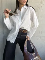 Camisa blanca de algodón con bordado inglés, corte clásico, cuello camisero y mangas largas con puños abotonados.