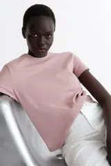 Remera de punto de algodón tupido color rosado, con cuello redondo ribeteado acanalado y mangas cortas.