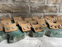 Aros tipo botón (studs) con piedras druzy negras o grises, engastadas en bisel dorado.