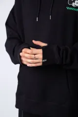 Buzo tipo canguro color negro con capucha y cordones ajustables. Presenta un pequeño estampado en el pecho con la silueta de Mickey Mouse y un detalle a cuadros en color verde.