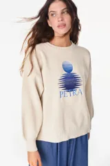 Sweater de punto color amarillo claro, con cuello redondo y diseño holgado. Cuenta con un bordado central en el pecho que representa un sol con su reflejo y la inscripción "PETRA" en tonos naranjas.