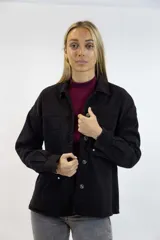 Camisa de jean negra de corte oversize, con bolsillos frontales con solapa y cierre de botones metálicos.
